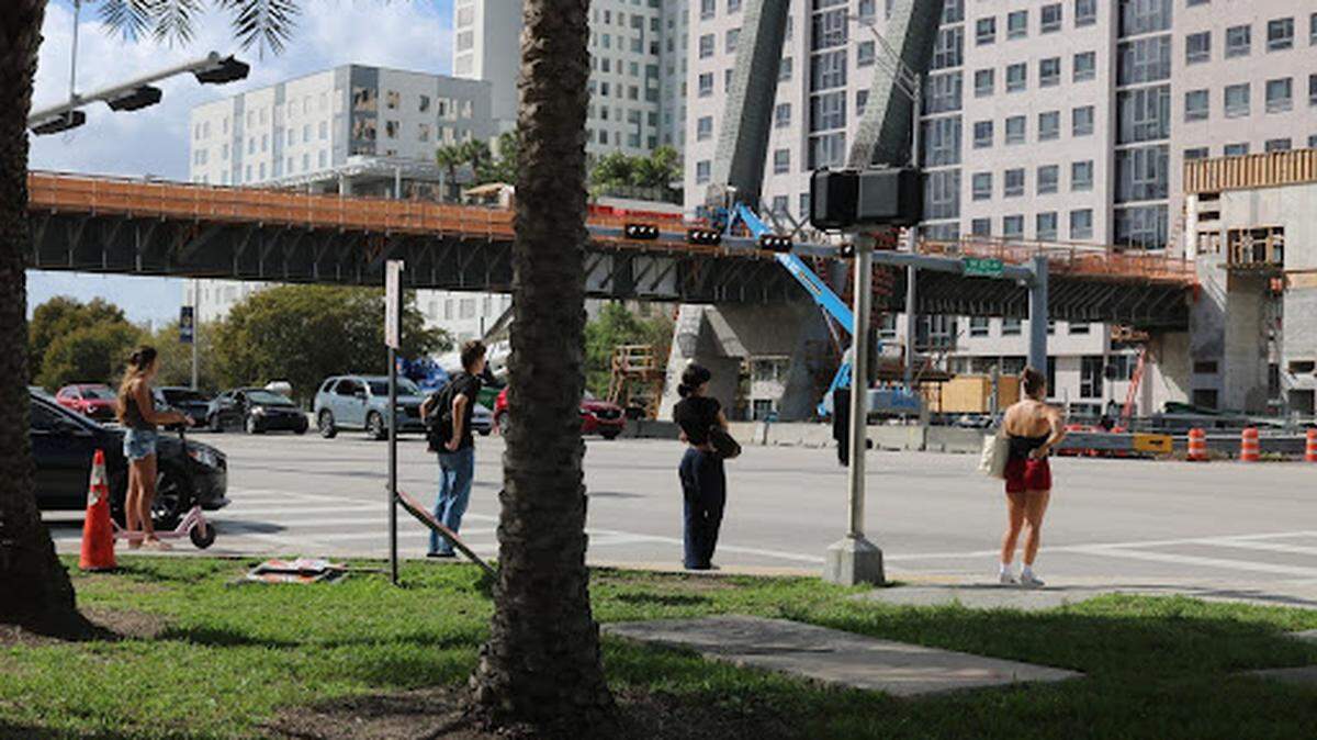Pedestrians wait to cross Southwest Eighth Street.