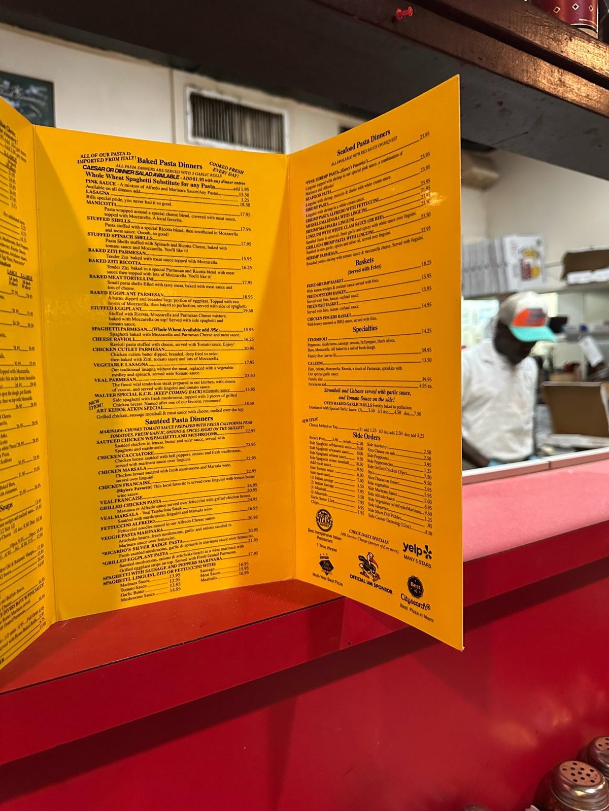 A laminated Big Cheese menu with co-founder Bill Archer’s folksy descriptions of his Italian specialties on the counter bar where the pizzas are made on March 5, 2025.