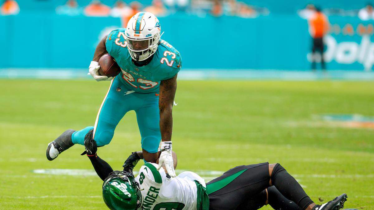 Miami Dolphins running back Jeff Wilson Jr. (23) runs the football against New York Jets linebacker Kwon Alexander (9) during the second quarter of an NFL football game at Hard Rock Stadium on Sunday, January 8, 2023 in Miami Gardens, Florida.