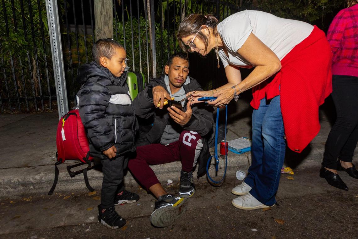 Hermanos de la Calle executive director Malena Legarre speaks with Venezuelan immigrants Enderson Reano, 27, and his son Jefferson, 4, to assist with shelter during a Christmas food distribution event on NW 17th Street in Miami, Florida, on Friday, December 22, 2023.