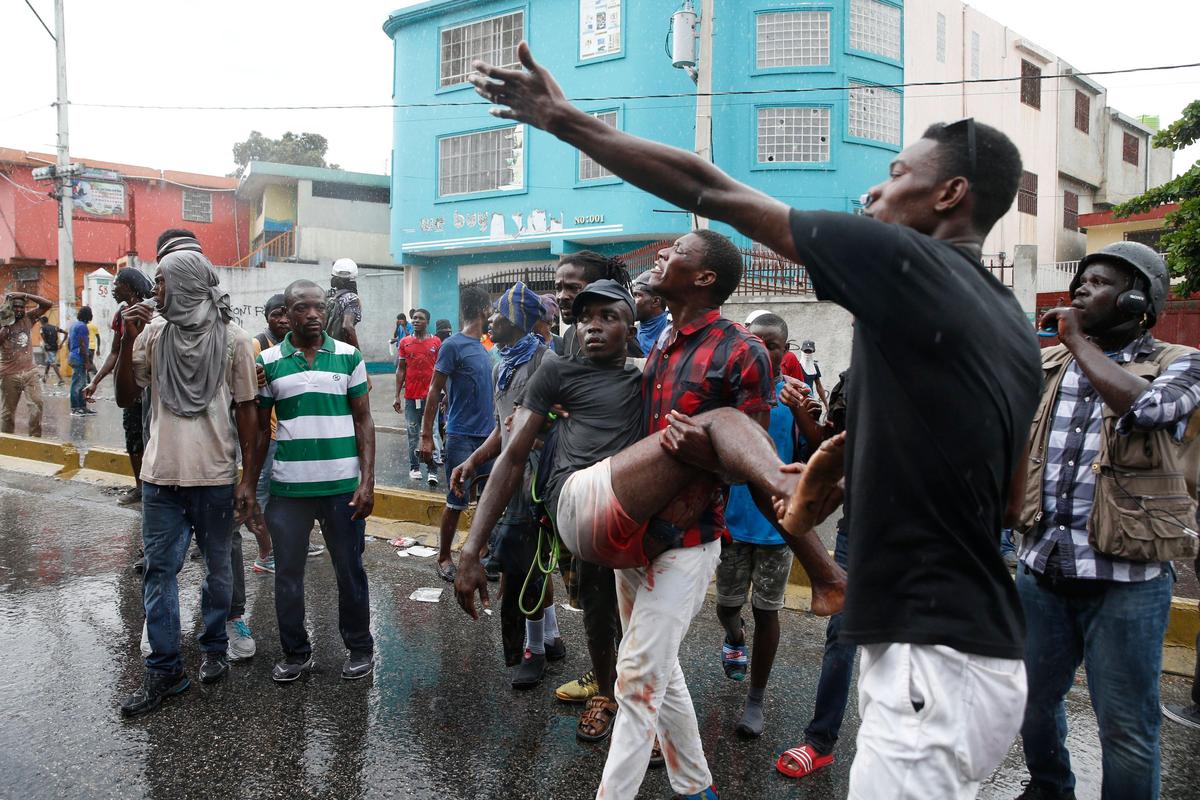 An injured protester is carried to safety during a nationwide push to block streets and paralyze the country’s economy as protesters press for President Jovenel Moise to give up power, in Port-au-Prince, Haiti, Monday, Sept. 30, 2019. 