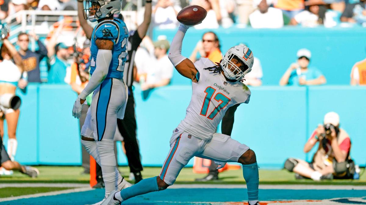 Miami Dolphins wide receiver Jaylen Waddle (17) reacts after scoring a touchdown against Carolina Panthers cornerback Donte Jackson (26) and Panthers middle linebacker Jermaine Carter (4) during the second quarter of an NFL football game at Hard Rock Stadium on Sunday, November 28, 2021 in Miami Gardens, Florida.