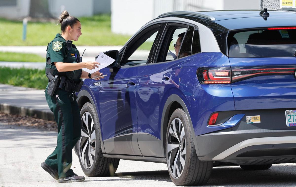 A Broward County Sheriff officer greets visitors as they arrive to visit the crime scene of the 2018 Parkland shooting in the 1200 building of Marjory Stoneman Douglas High School Thursday, July 6, 2023. The school district plans to demolish the building.