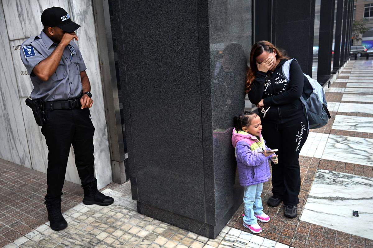 A security guard breaks down in tears while witnessing the heartbreak of a migrant woman and her child after her husband was detained by ICE as they left his immigration court hearing at the Jacob Javits Federal Building in New York on Aug. 20, 2025.