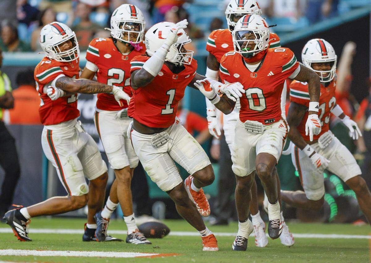 Miami Hurricanes linebacker Mohamed Toure (1) and defensive back Keionte Scott (0) celebrate Scott's pick six in the first half during an NCAA football game at Hard Rock Stadium against Syracuse Orange in Miami Gardens, Florida on Saturday, November 8, 2025.