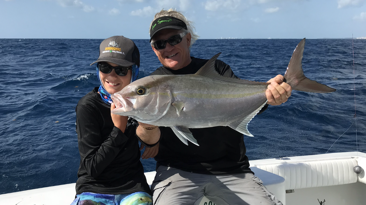 Matthew Utter, 10, of Hollywood with a nice almaco jack that he caught fishing on Free Spool with Capt. Dennis Forgione, right.