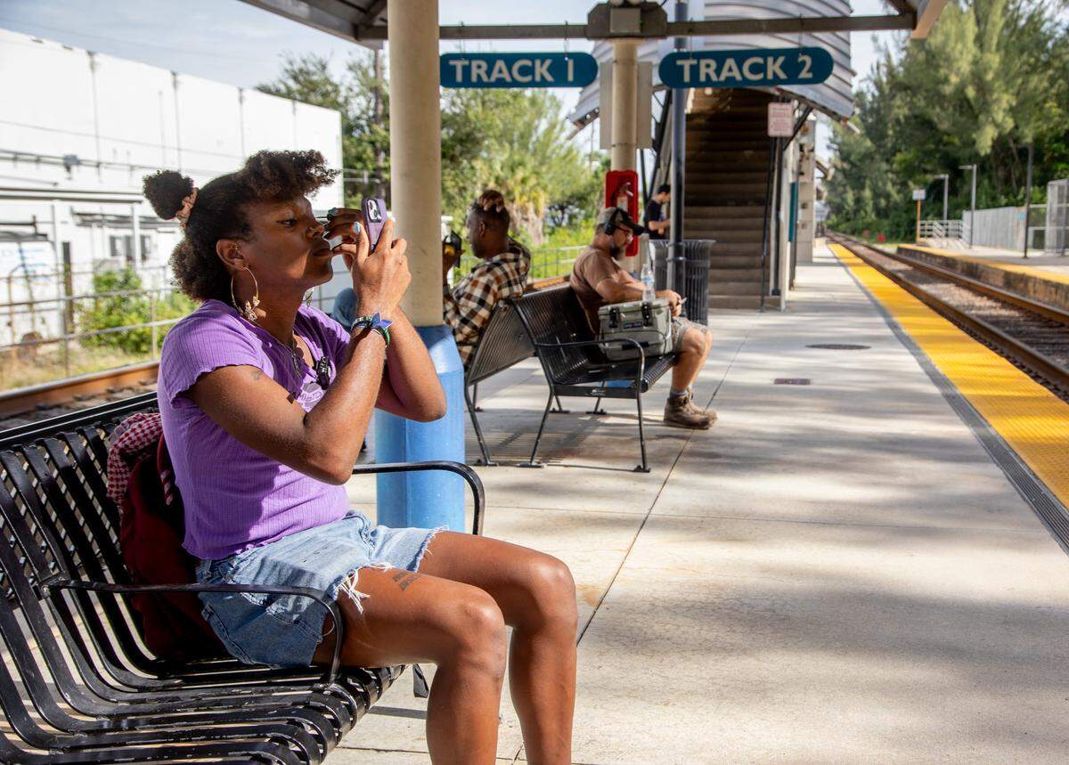 Z Spicer puts on eyeliner while waiting for the Tri-Rail as part of their commute to work in Little Havana.