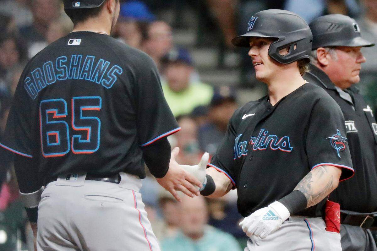 Miami Marlins’ Peyton Burdick, right, high-fives Jordan Groshans, left, after they scored on his two-run home run against the Milwaukee Brewers during the third inning of a baseball game, Saturday, Oct. 1, 2022, in Milwaukee. (AP Photo/Jon Durr)