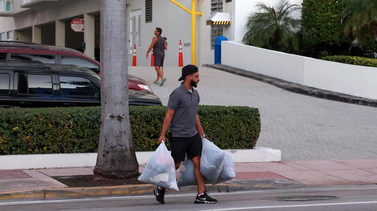 A resident crosses the street carrying bags outside the Port Royale Condominium at 6969 Collins Ave., Miami Beach, after tenants were told to evacuate by 7 p.m. due to structural concerns on Thursday, Oct. 27, 2022.