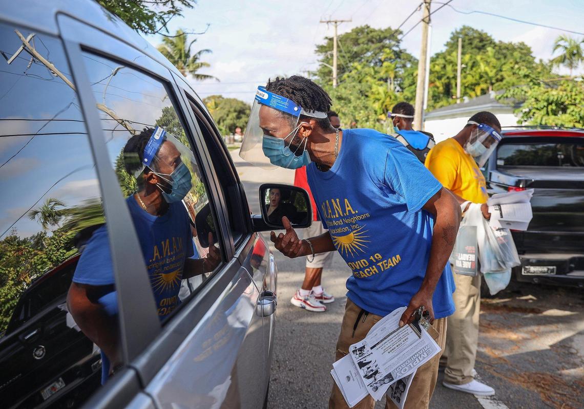 On Wednesday, December 16, 2020 Calvin Wyche, 35, center, speaks to a resident while walking through Miami’s Brownsville neighbor handing out employment and COVID-19 information in Miami’s Brownville neighborhood. Members of the Neighbors And Neighbors Association’s (N.A.N.A.) COVID 19 Outreach Team talked to motorists, homeowners, and other residents as they spread the word about COVID-19 in the areas hardest hit by the virus. The three-man group handed out PPE as well as a survey that asks residents about how COVID has affected them. While not explicitly asking about the vaccine, many have heard hesitancy, specifically from Black and brown residents.