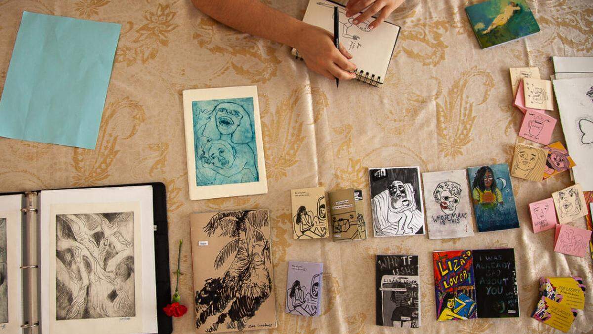 Table of zines and prints by Zoe Lackey.