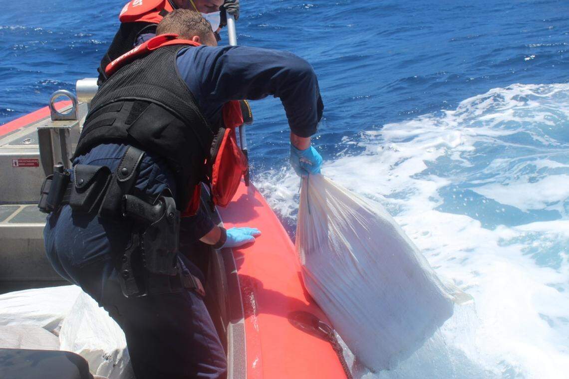 A crewman on the U.S. Coast Guard Cutter Heriberto Hernandez pulls a bale of cocaine that the Coast Guard said a speedboat threw overboard while under pursuit.
