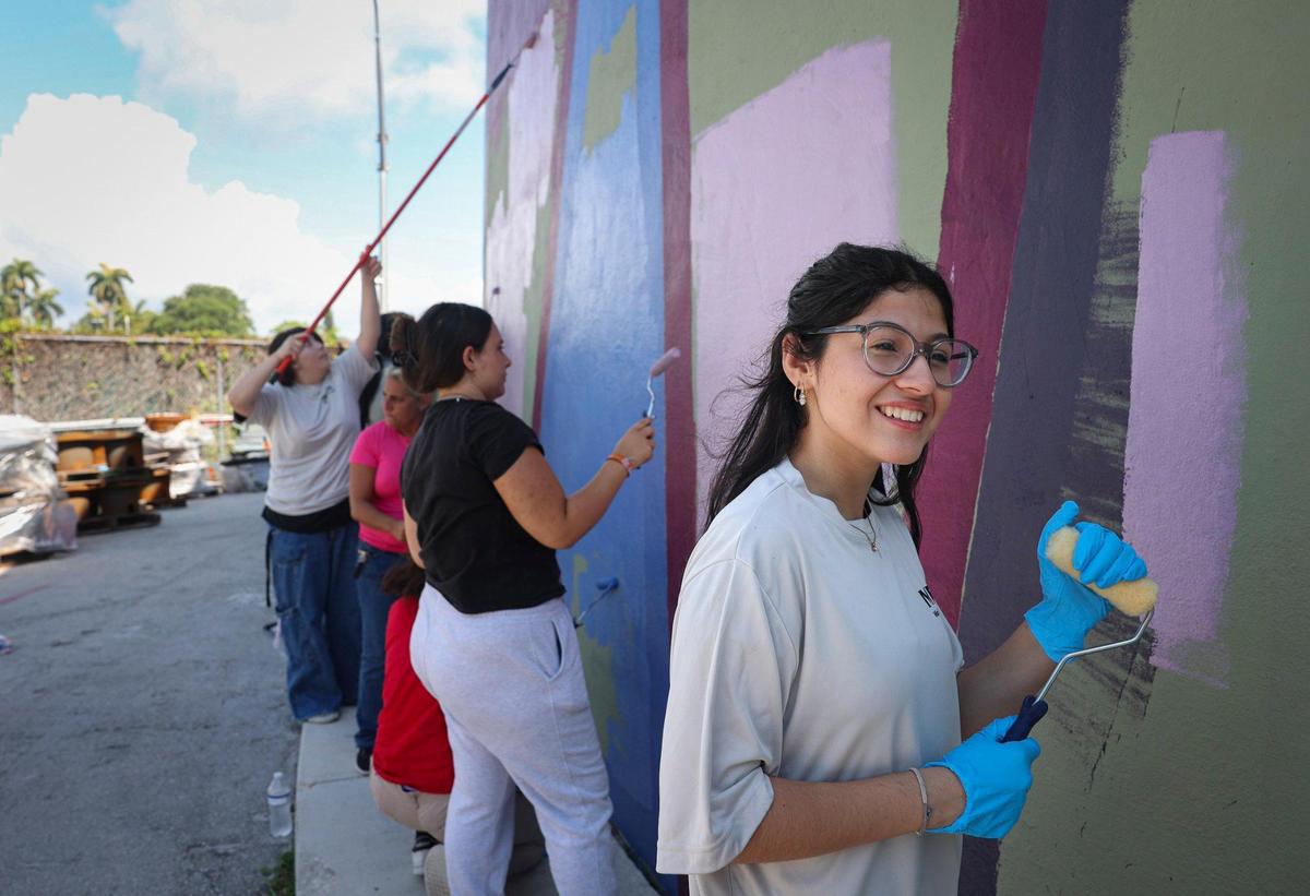 Maia Ottaggio, a student at Miami Beach Senior High School, paints a mural onto a Miami Beach water tank Wednesday, April 26, 2023. The mural features a line from the poem by Beach High student Valentina Mena in a project by O, Miami poetry festival and a Boa Mistura, a Madrid-based art collaborative.