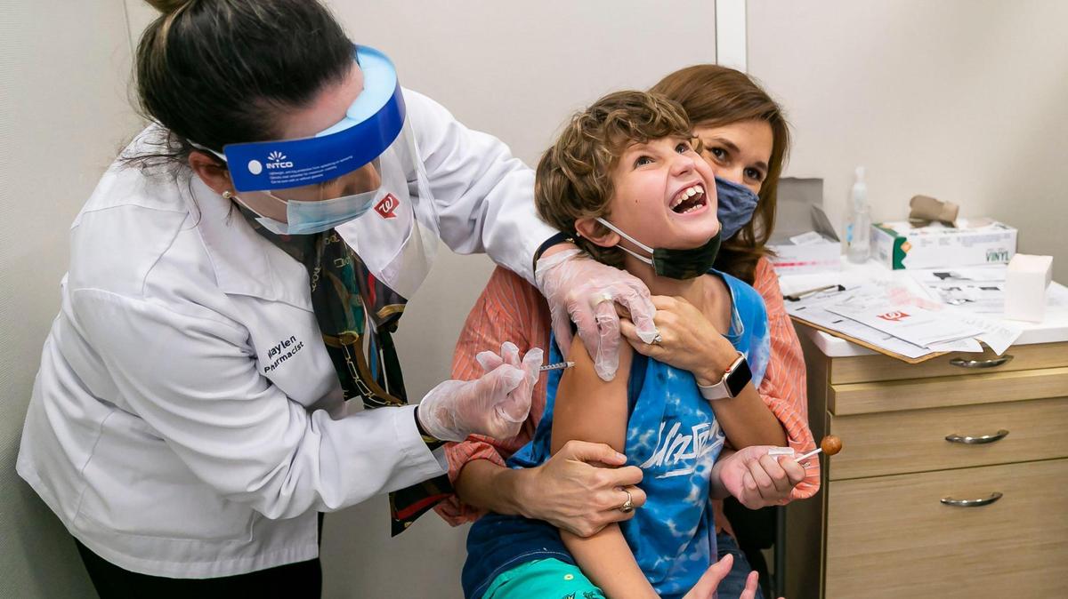 Leo Johnson, de 8años, reacciona cuando la farmacéutica Maylen Mesa le administra la vacuna de Pfizer-BioNTech en un Walgreens de Miami, Florida, el sábado 6 de noviembre de 2021. La madre de Leo, Allison Johnson, de 41 años, ayuda a controlarlo.