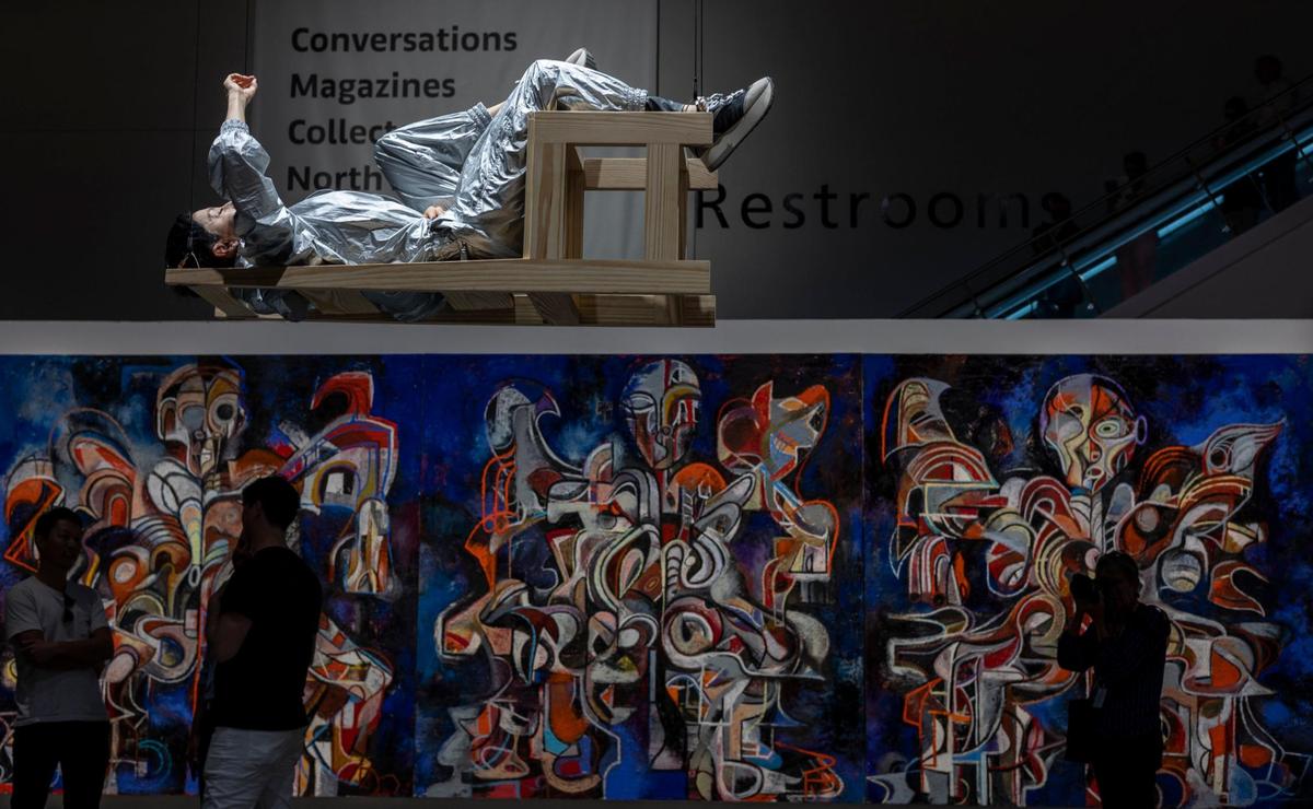 Artist María José Arjona performs in her interactive work, “Chair,” above the floor at the Meridians sector. Zio Ziegler’s “The Journey through the Tehom I, II, III” serving as a backdrop during the Art Basel VIP opening day. At the Miami Beach Convention Center.