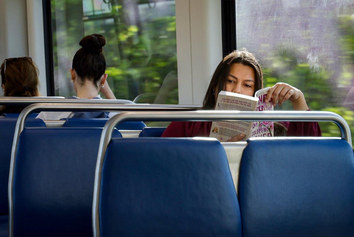 Elizabeth Prats, an HR director, right, enjoys a book during her 50-minute commute from Dadeland North to the Government Center on Wednesday, July 24, 2024, in Miami. Prats said she would vote in favor expansion of transit.