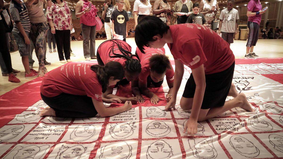 Miami, Florida, July 18, 2018 - Campers signed their names on the quilt as their parents and other guests shot pictures and videos during the Arsht Center’s AileyCamp Miami 10th anniversary celebration and Quilt reveal.

The Arsht Center’s AileyCamp Miami campers revealed a 4,000 square foot quilt on the Knight Concert Hall stage, showing sketch images of themselves, with personal words they traced on their profile to mark the 10th Anniversary of the program.

AileyCamp Miami is a full scholarship, six-week summer program that has transformed the lives of over 900 underserved students from Miami-Dade County Public Middle schools since its inception in 2008. The program strives to provide a safe and artistic environment for students to take West African, Jazz, Modern, and Ballet dance classes while also learning about nutrition, conflict resolution, drug prevention, critical thinking and other life skills in Personal Development and Creative Communication classes.
