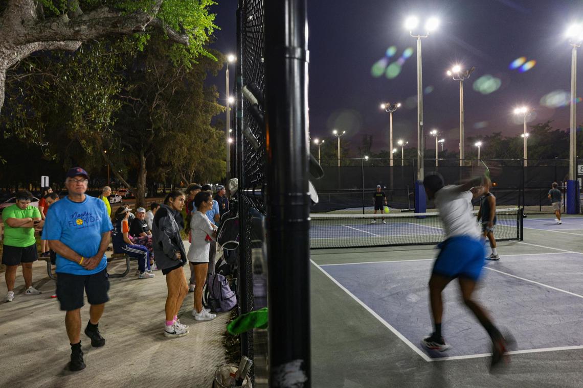 People wait outside the fence to play pickleball while pickup games take place at Tropical Park courts on Monday, Feb. 13, 2023, in Miami-Dade.