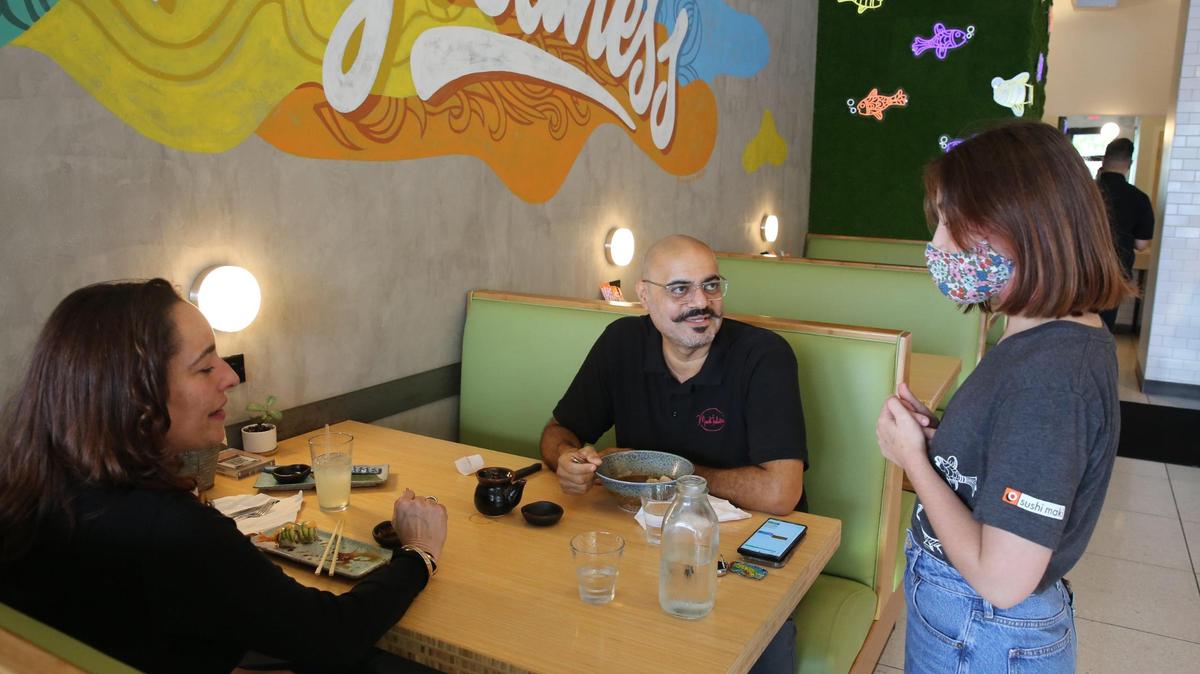 Mary Catherine Lorié, 19, checks on customers Linnette Rousseau and Joe Gebara as they enjoy a late afternoon meal at Sushi Maki in Dadeland. Lorié is one of several teen employees who found summer employment at the restaurant.