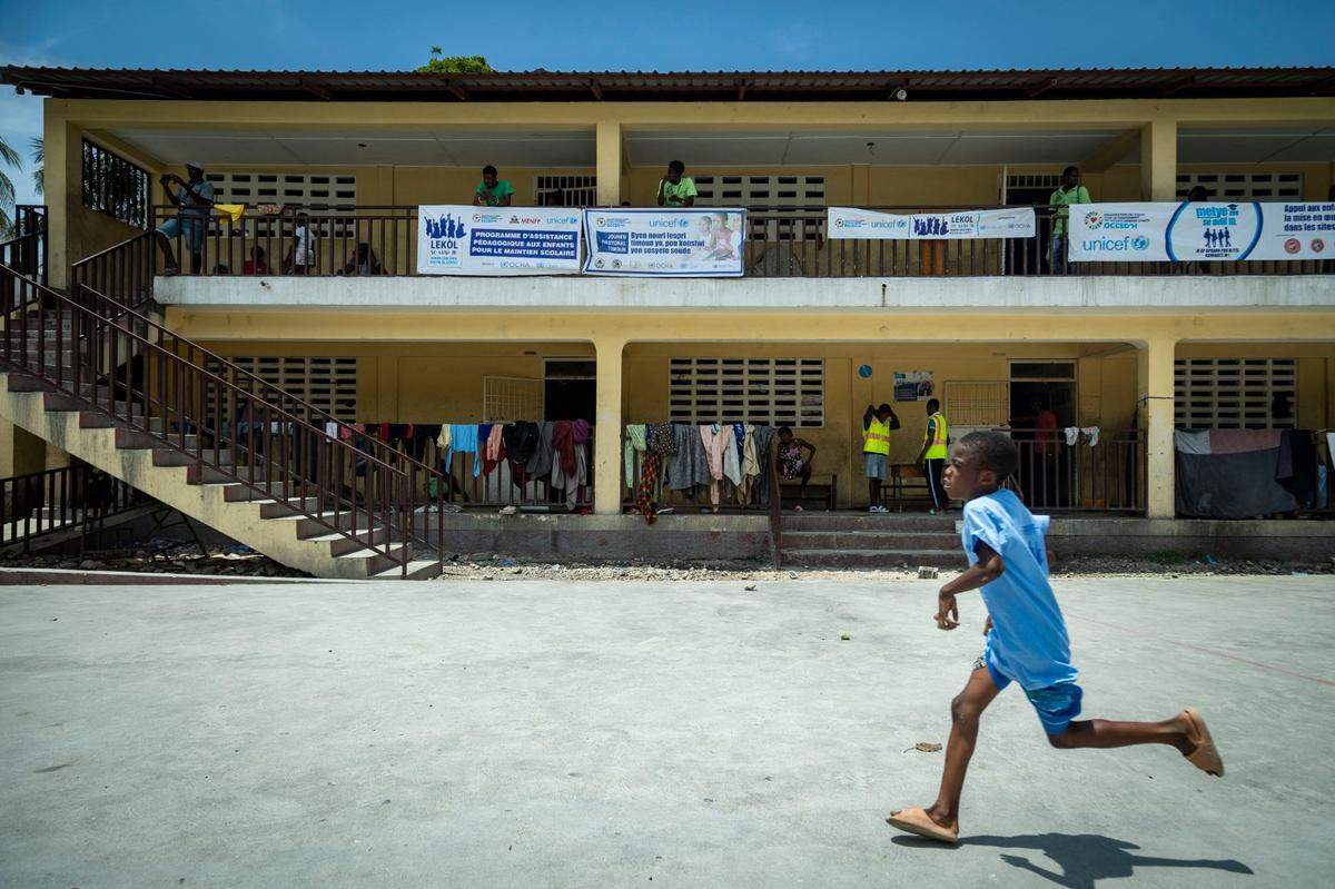 A boy runs across the schoolyard at Ecole National Joseph C. Bernard DeFreres displacement camp in Port-au-Prince, Haiti, on Aug. 27, 2024. Residents who have been forced to abandon their homes due to gang violence have sought refuge in this school rather than face the consequences of staying in gang-occupied territory.