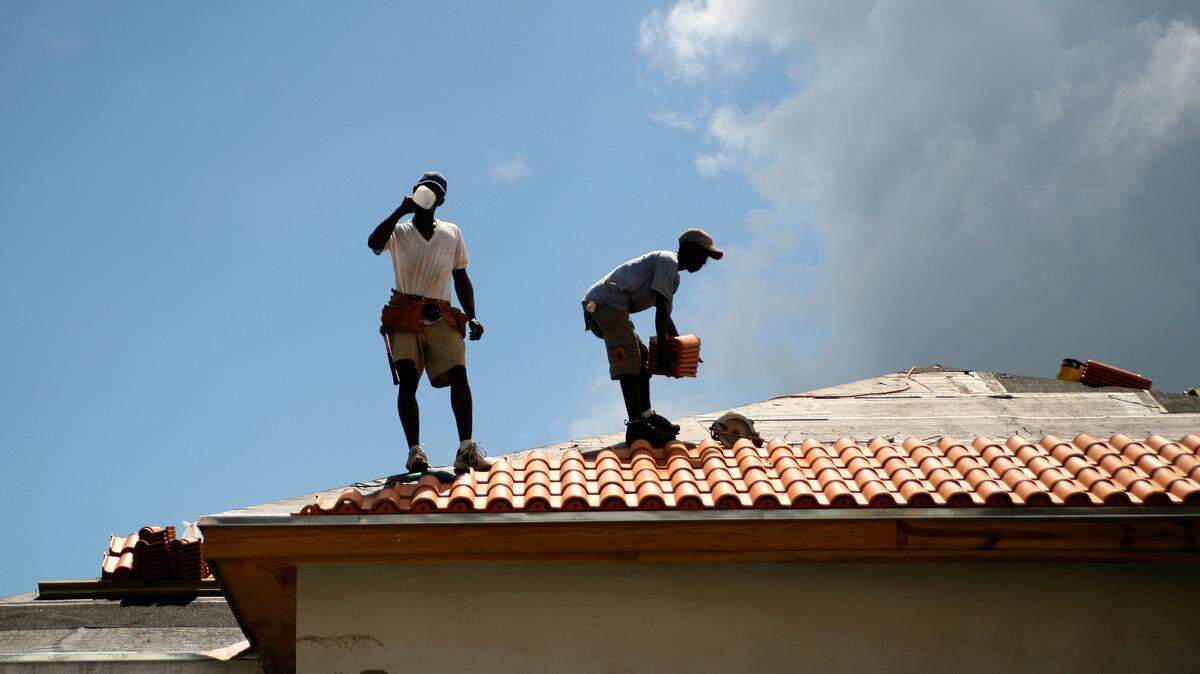 Men working on roof on hot day.