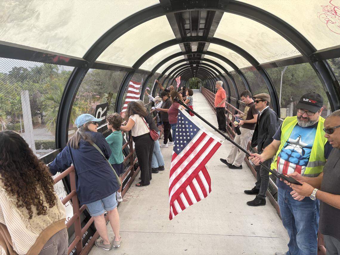 Protesters stand on the Vizcaya pedestrian bridge in Miami Monday, Jan. 12, 2026, to demonstrate against U.S. Immigration and Customs Enforcement and the Trump administration.