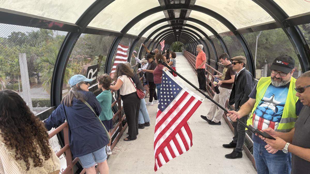 Protesters stand on the Vizcaya pedestrian bridge Monday, Jan. 12, 2026, to demonstrate against U.S. Immigration and Customs Enforcement and the Trump administration.