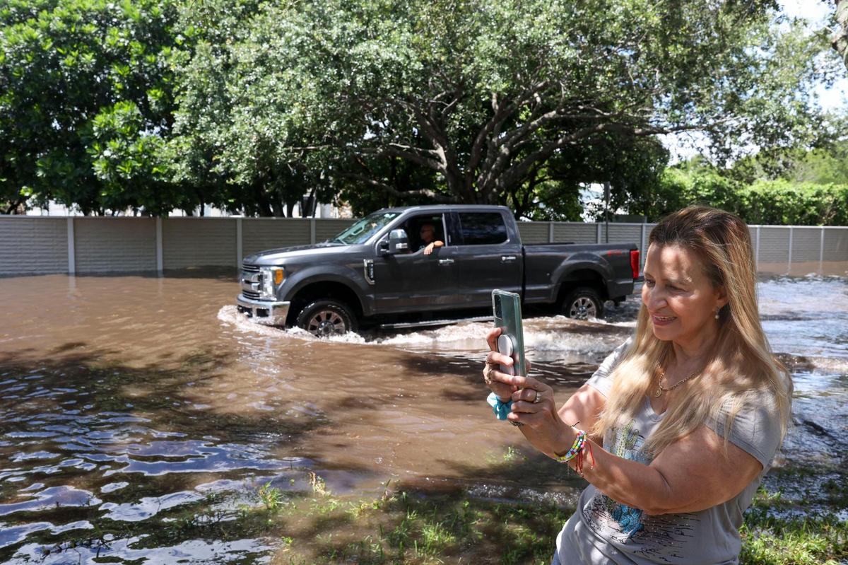 Zoara Guzman, resident of Cutler Bay, talks to her family that has been at her daughter’s house on the other side of the flooding on Southwest 196th Street on Tuesday, June 7, 2022, following the weekend storms.