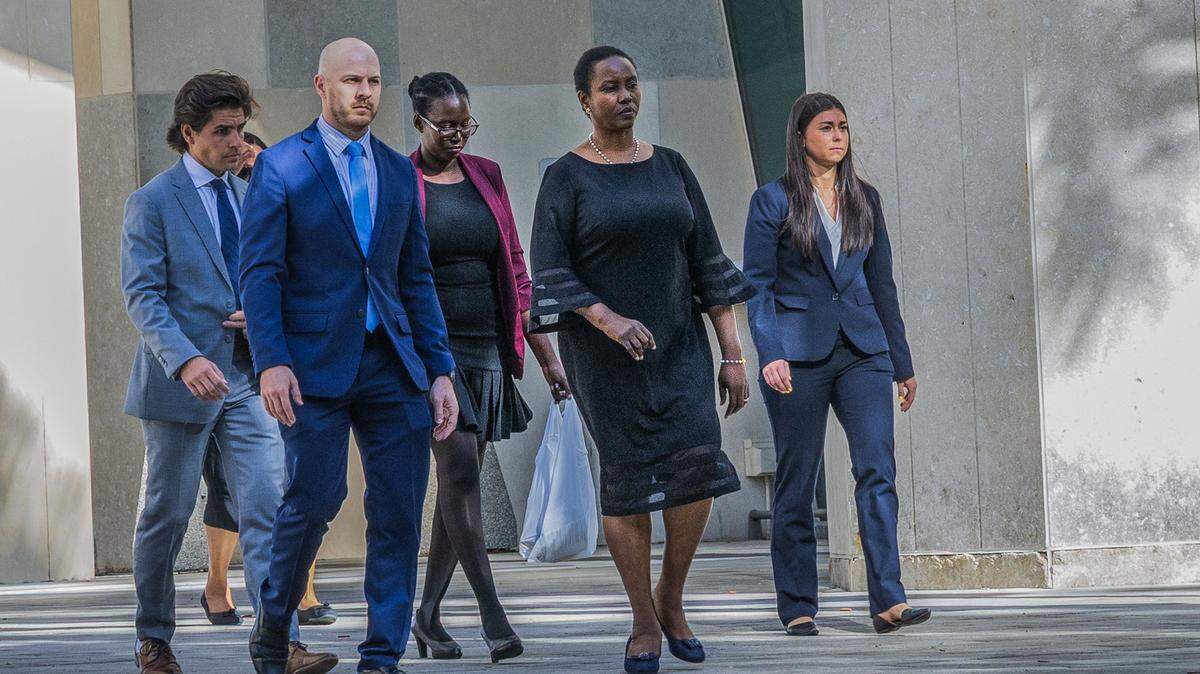 Officials with the U.S. Department of Justice and security personnel accompanied Martine Moïse (second from right), widow of Haitian President Jovenel Moïse, and her daughter Jormalie Moïse (center) as they leave the Wilkie D. Ferguson Jr.  Courthouse in Miami after testifying for the second day as the government’s first witness on Wednesday, March 11, 2026.
