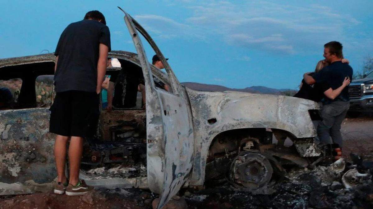 Relatives see what is left of a car in which family members were killed in the state of Sonora in Mexico.