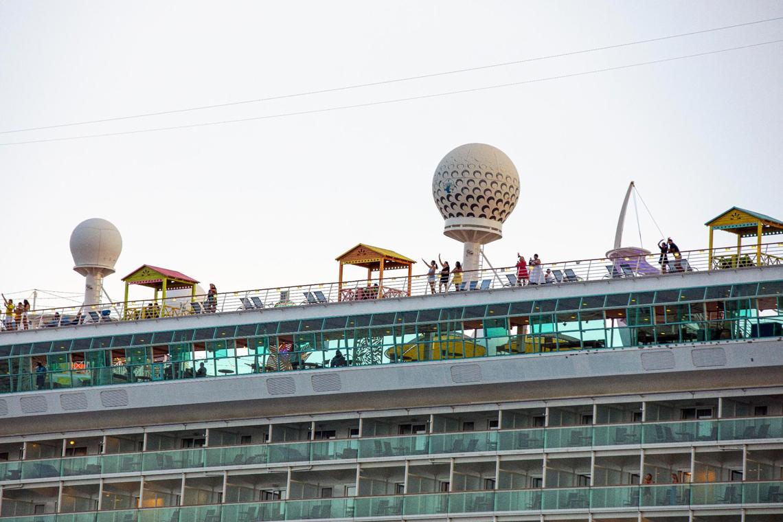 Employee volunteers wave from Royal Caribbean International’s Freedom of the Seas cruise ship as it sets off down Government Cut for a simulated voyage leaving from PortMiami in Miami, Florida, on Sunday, June 20, 2021. In accordance with CDC requirements, the purpose of the simulation is to observe the cruise line’s multilayered health and safety measures.