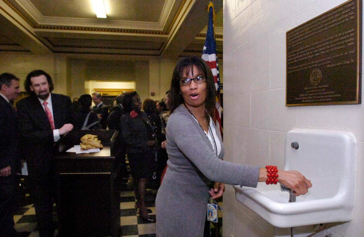 A commemorative plaque was placed over this fountain, on the sixth floor of the Miami-Dade County Courthouse in 2009, in honor of Black History Month, by the Dade County Bar Association, in collaboration with the Gwen S. Cherry Black Women Lawyers Association, Haitian Lawyers Association, and Wilkie D. Ferguson Jr. Bar Association. The drinking fountain was once segregated and now the plaque affirms the hope for equal justice for all. Angela Gibson of the juvenile services department checks out the original water fountain to see if it still works.