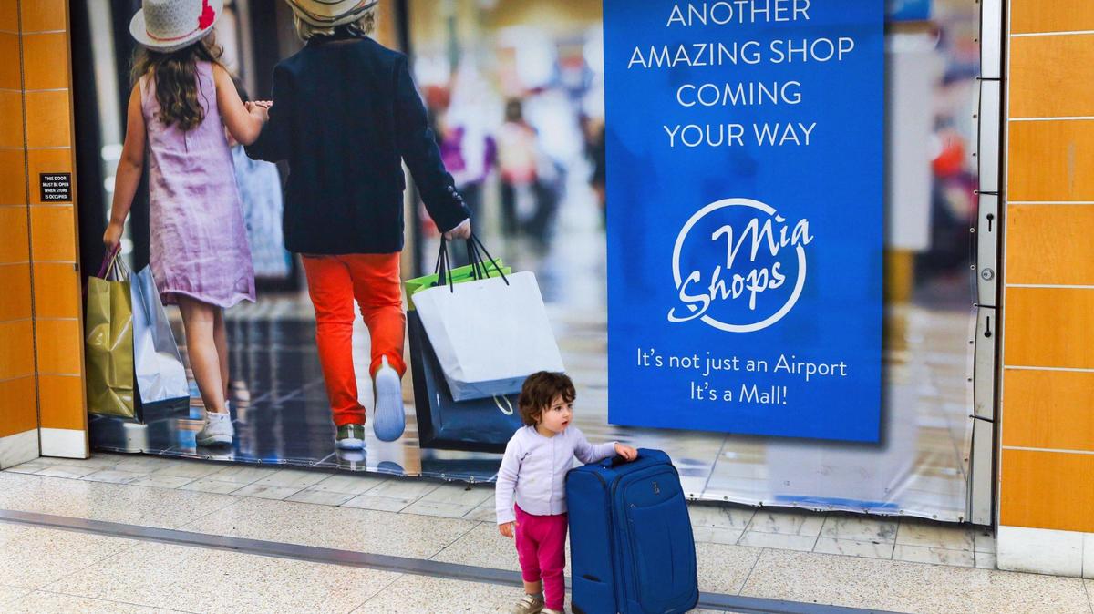 Baltimore native Naomi Peth, 2, hangs onto her mother’s luggage while standing by a storefront at Miami International Airport.