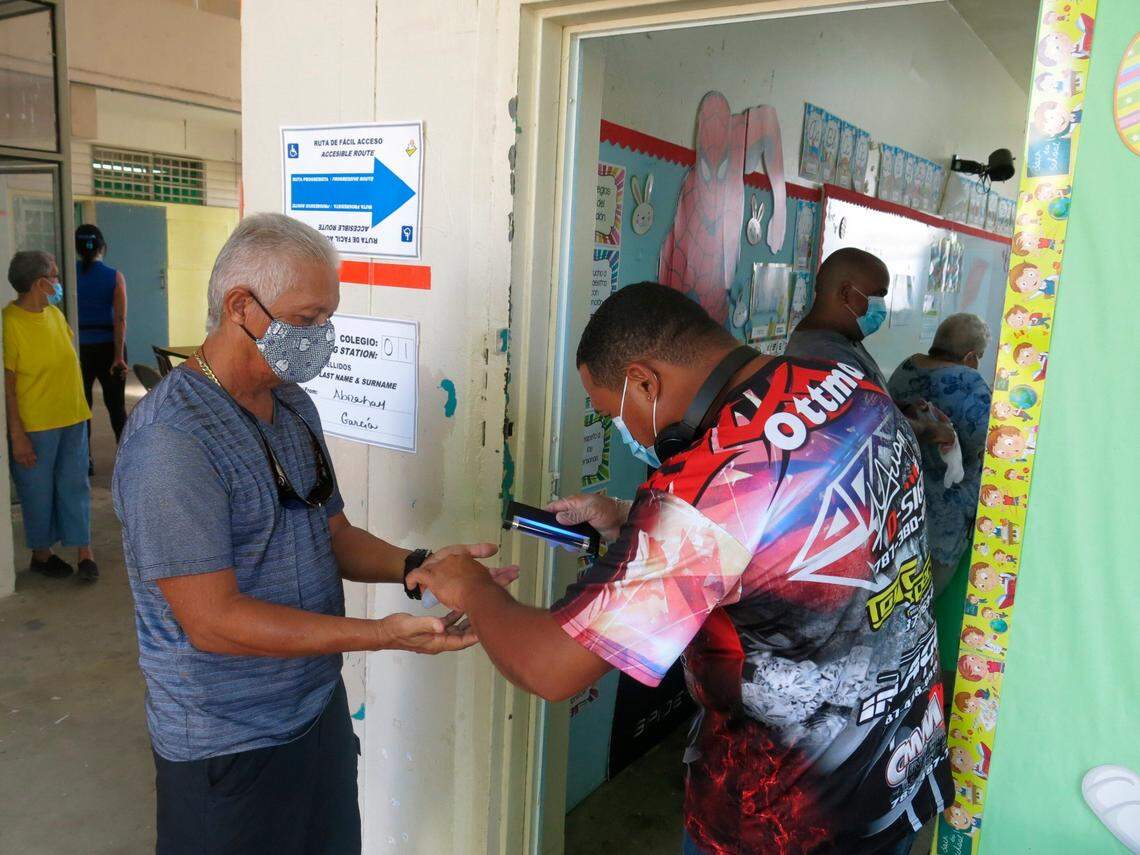 A volunteer scans a voter’s hands before he casts his ballot in LoÃ­za, Puerto Rico, Sunday, Aug. 16, 2020. Thousands of Puerto Ricans on Sunday got a second chance to vote for the first time, a week after delayed and missing ballots marred the original primaries in a blow to the U.S. territory’s democracy. 