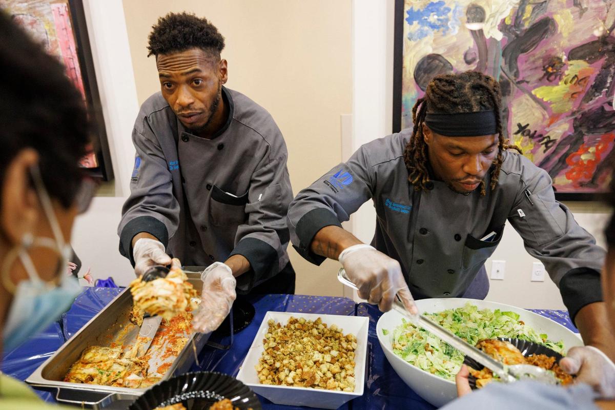 Allen James, left, and Kitchen Cook classmate Dennis Cherry, right, serve people after their graduation ceremony on Wednesday, Sept. 11, 2024, at Camillus House in Miami. “When you create these programs and give one of us a shot, we’re gonna take it,” said Cherry.