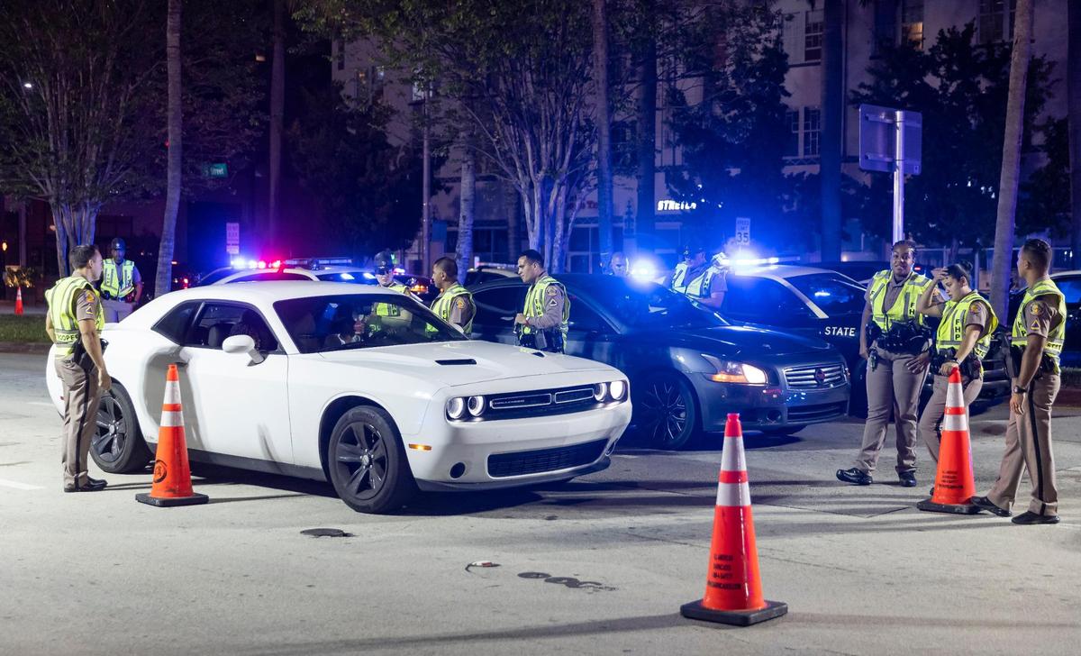 A group of Florida Highway Patrol officers stop a driver at a checkpoint along 5th Street on Friday, March 24, 2023 in Miami Beach, Fla. After two deadly shootings, city officials voted not to re-impose a midnight curfew, but implemented an emergency order banning alcohol sales after 6 p.m.