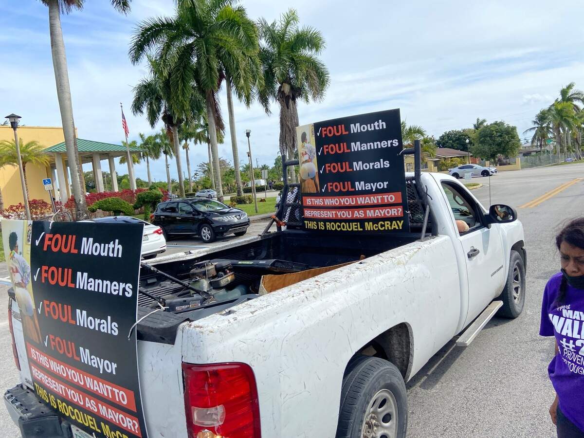 A pickup truck with signs attacking Rocquel McCray’s online activity drives past supporters of both candidates outside Florida City City Hall Tuesday, Feb. 15, 2022.