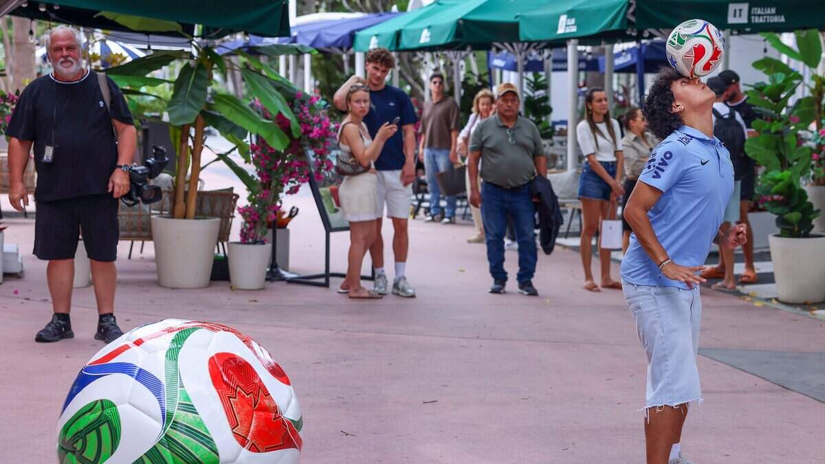 St. Thomas University soccer player Ricky Martinez, 22, balances a soccer ball on his head while he and others wait to enter the new FIFA World Cup store on Lincoln Road Mall in Miami Beach, Florida.
