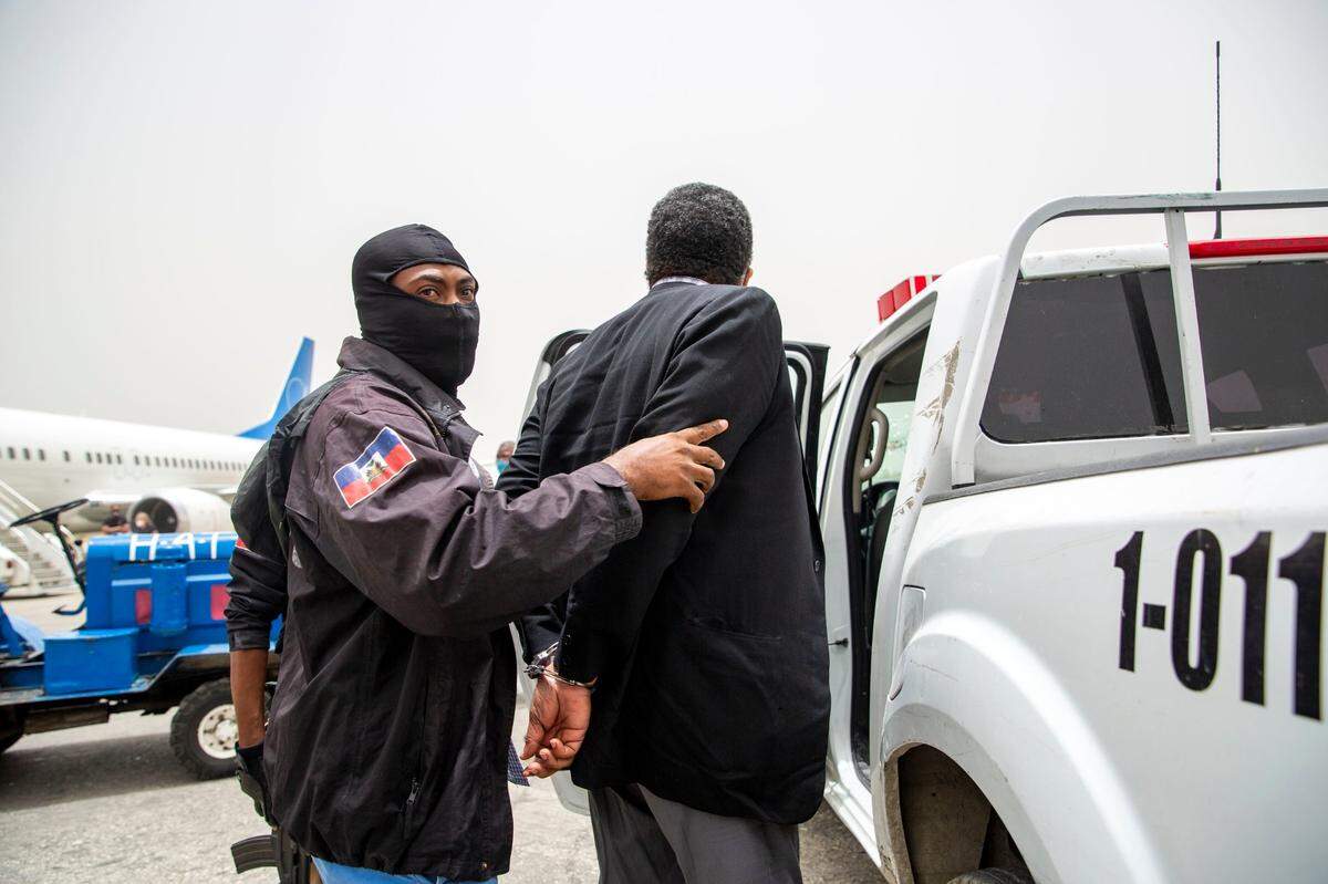 Former paramilitary leader Emmanuel Constant is detained by Haitian police at his arrival to the Toussaint Louverture International Airport in Port-au-Prince, Haiti, Tuesday, June 23, 2020. 