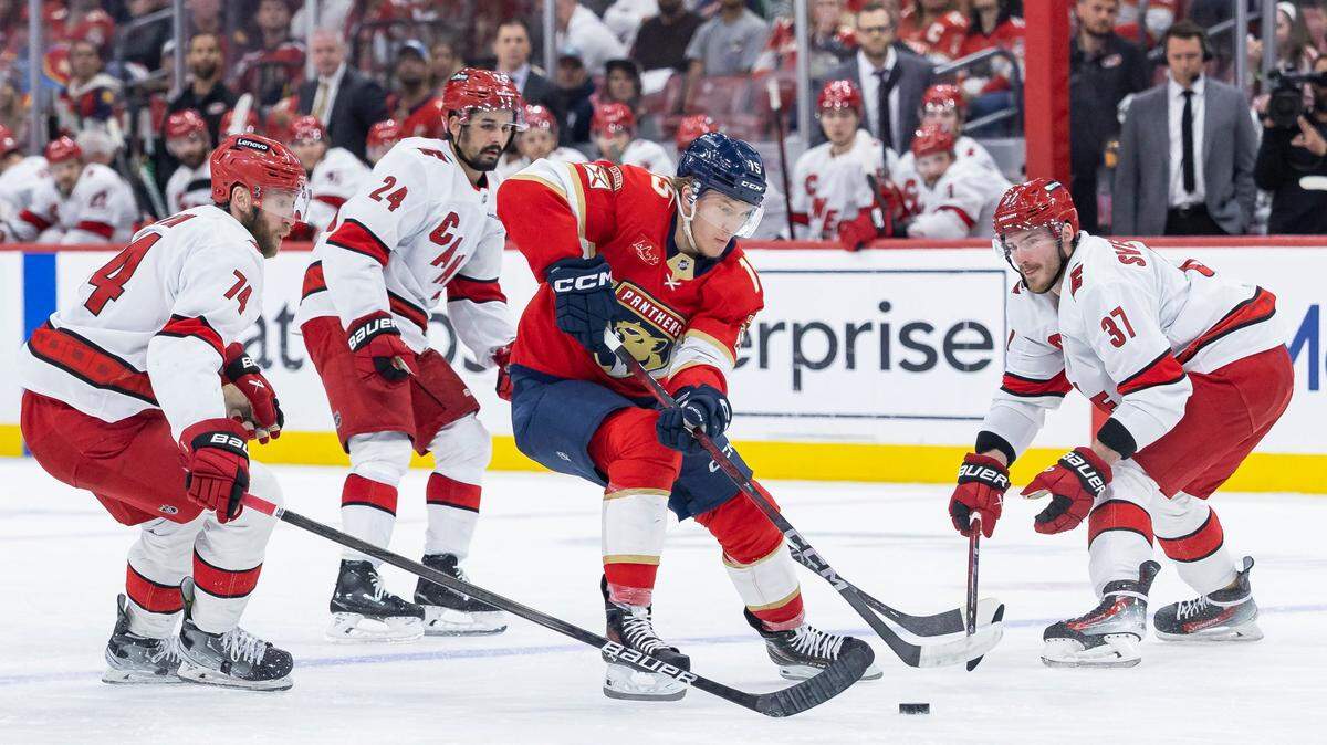 Florida Panthers center Anton Lundell (15) competes for the puck against Carolina Hurricanes defenseman Jaccob Slavin (74) and right wing Andrei Svechnikov (37) in the second period of Game 4 during the Eastern Conference final of the NHL Stanley Cup playoffs at Amerant Bank Arena on Monday, May 26, 2025, in Sunrise, Fla.