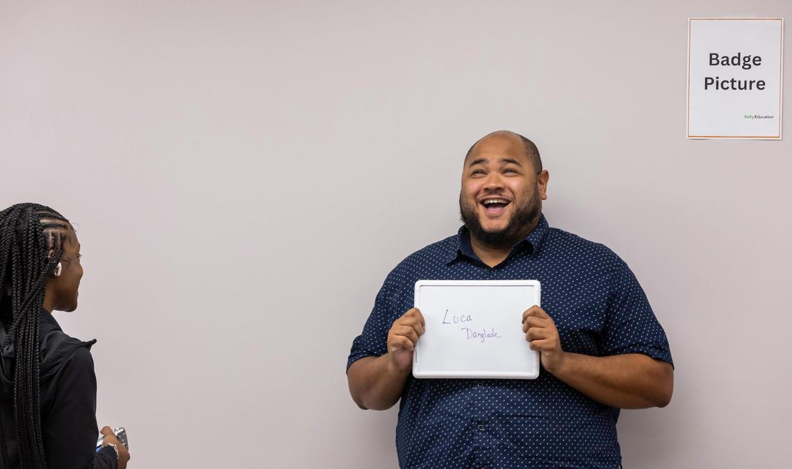 Daijah Lee, an onboarding specialist with Kelly Education, prepares to take a badge photo of Luca Danglade, 32, as he goes through the procedures to become a Miami-Dade Schools substitute teacher at the Kelly Education offices on Wednesday, Oct. 4, 2023, in Miami, Fla.