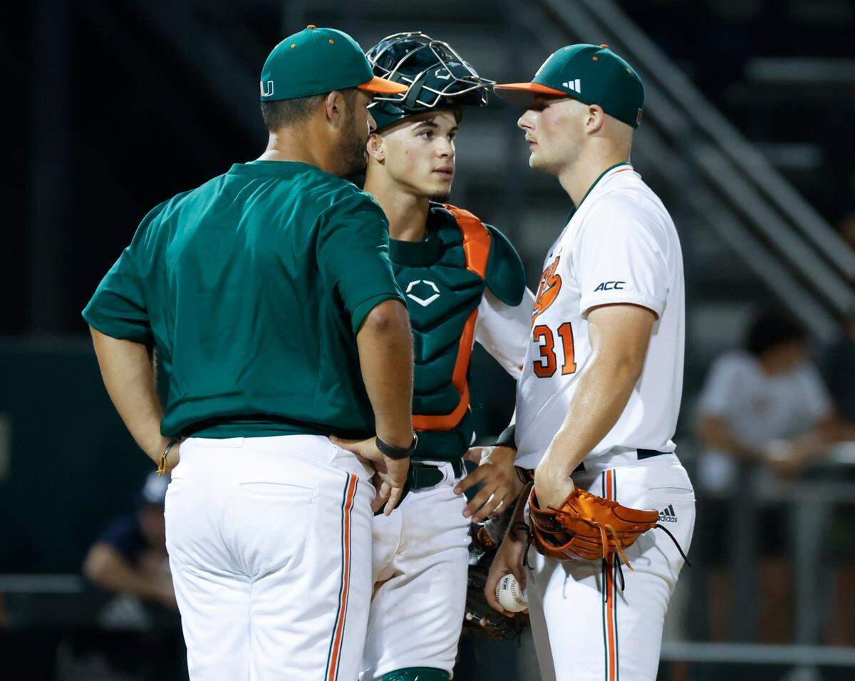 Miami Hurricanes catcher Carlos Perez (61) and pitching coach J.D Arteaga speak with starting pitcher Gage Ziehl (31) in the second inning against Penn State at Mark Light Field at Alex Rodriguez Park in Coral Gables, Florida on Friday, February 17, 2023.