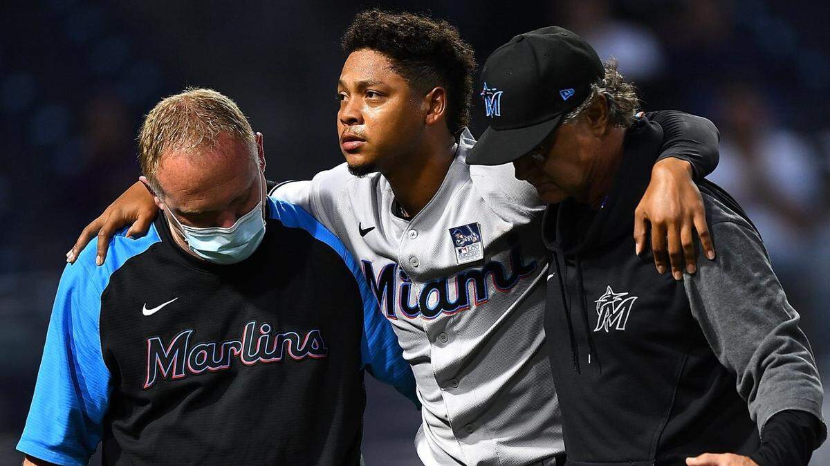 Elieser Hernandez #57 of the Miami Marlins is helped off the field after being injured while scoring during the sixth inning against the Pittsburgh Pirates at PNC Park on June 3, 2021 in Pittsburgh, Pennsylvania.