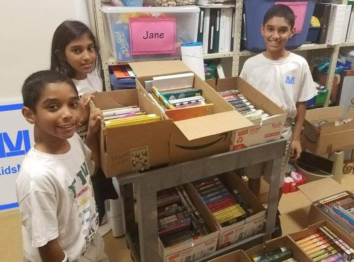 The Martoma siblings pose for a photo near books they plan to donate to prison waiting rooms.