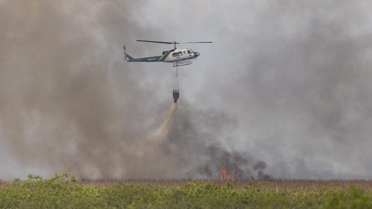 Florida Forest Service firefighters use a helicopter to carry water as they combat an Everglades wildfire near US Highway 27 on Thursday, Aug. 21, 2025, in South Florida.