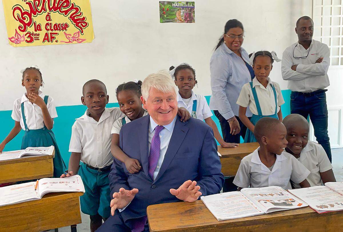 Denis O’Brien, the founder of Digicel Group, laughs with students at Institution Mixte Notre Dame de l’Assomption on Feb. 16 in Port-au-Prince. A school building constructed by his foundation and recently inaugurated bears the name of former Digicel Group CEO Colm Delves. During the visit, O’Brien agreed to help the Montfort Missionaries, who run the school, construct a new building.