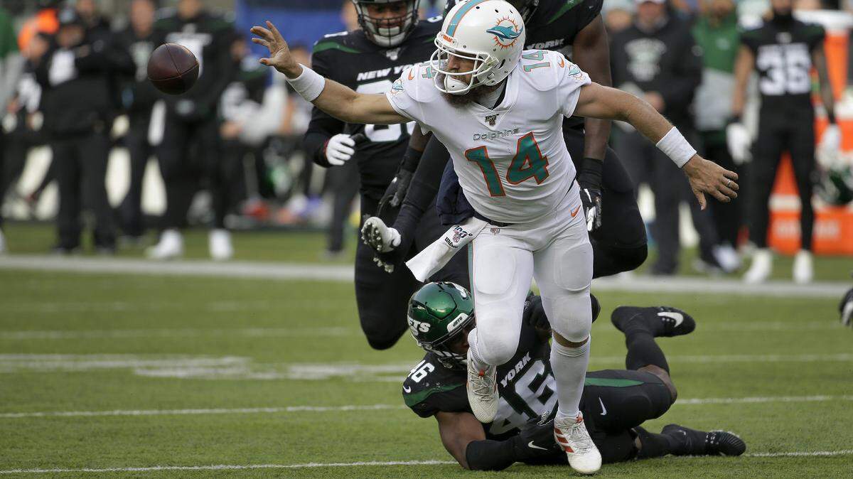 Miami Dolphins quarterback Ryan Fitzpatrick (14) flips a horizontal pass as he is tackled by New York Jets linebacker Neville Hewitt (46) during the second quarter of an NFL football game, Sunday, Dec. 8, 2019, in East Rutherford, N.J.