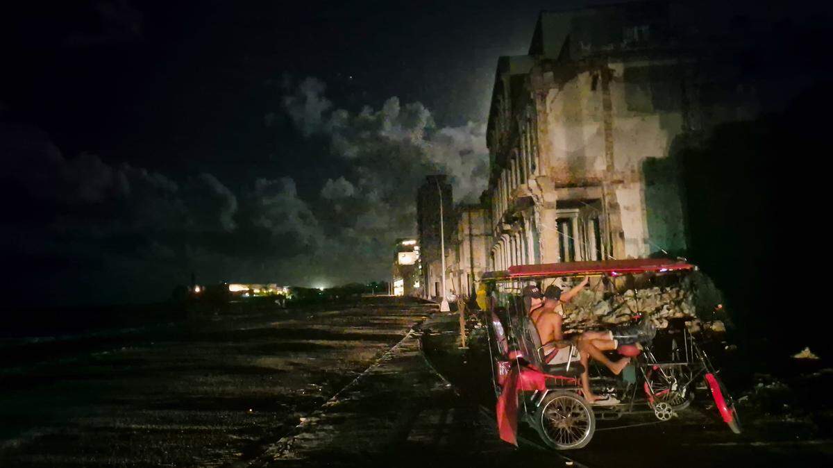 During a power outage, two men sit in a bicycle cab in Havana in October 2024.