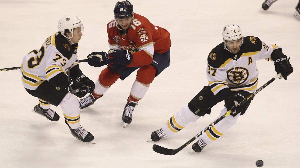 Boston Bruins’ Patrice Bergeron, right, moves the puck with Charlie McAvoy (73) as Florida Panthers’ Aleksander Barkov (16) defends during the first period of an NHL hockey game, Saturday, March 23, 2019, in Sunrise, Fla. (AP Photo/Luis M. Alvarez)