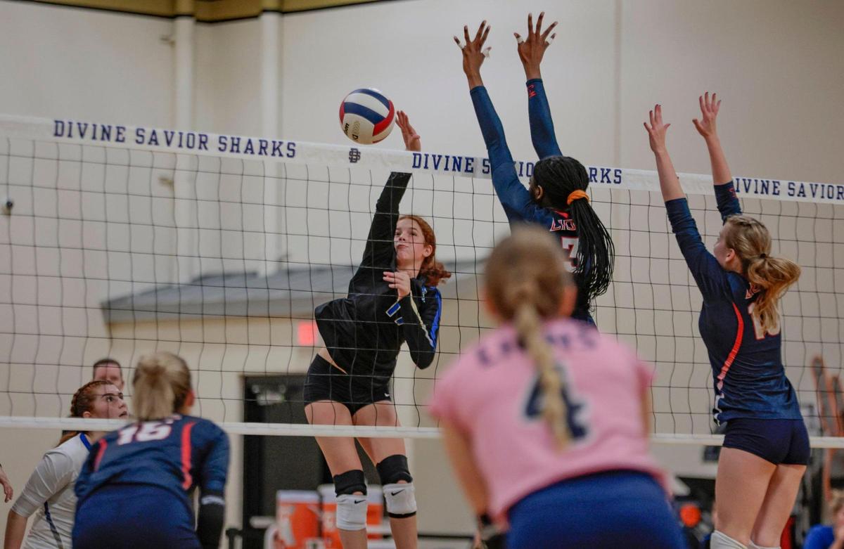 Divine Savior volleyball player Sasha Kawas (17) spikes the ball as Chaminade-Madonna’s Kendall Evans (3) and Lara Zima (10) defend at the net during the volleyball playoff at Divine Savior Academy on Friday, October 28, 2022.